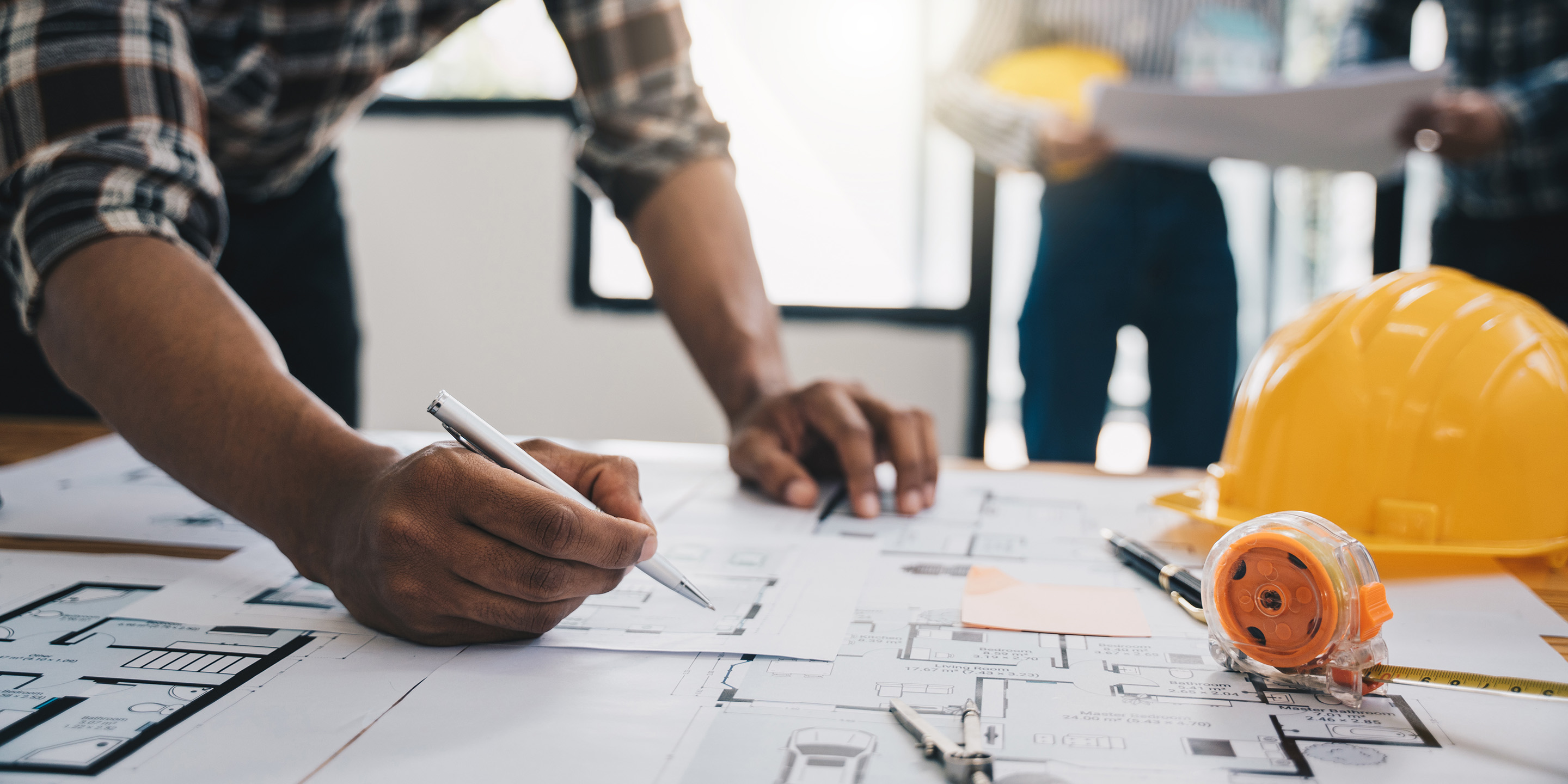 Blueprint and hardhat on desk.