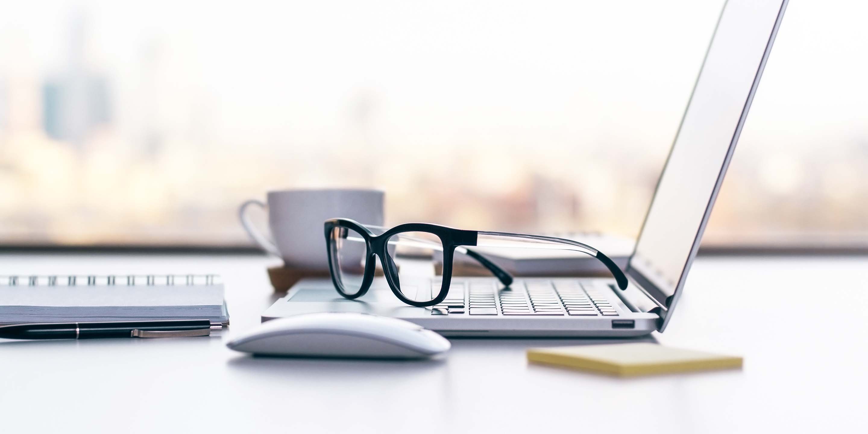 Eyeglasses resting on laptop on desk