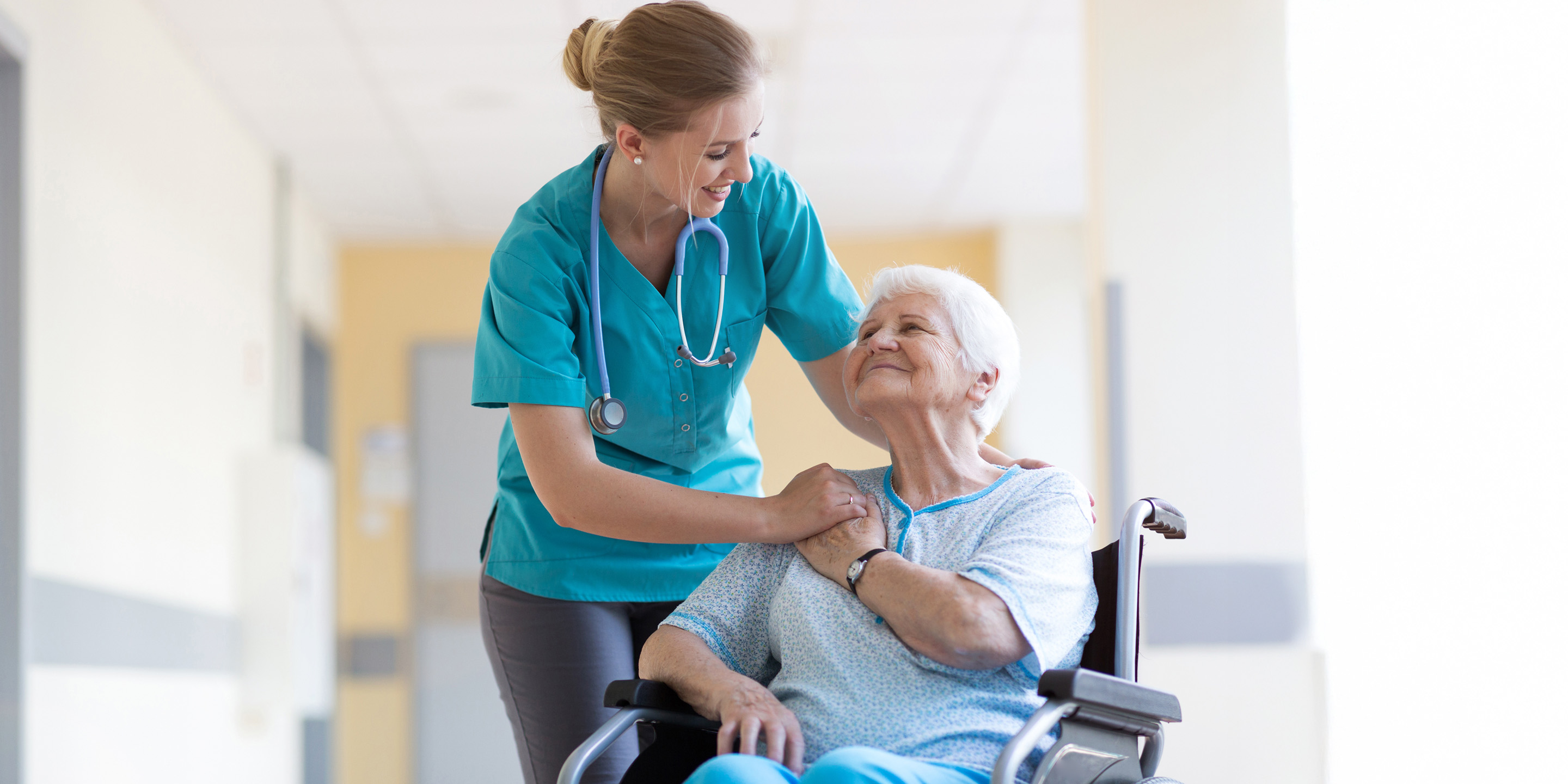 Nurse helps elderly patient seated in wheelchair with care.