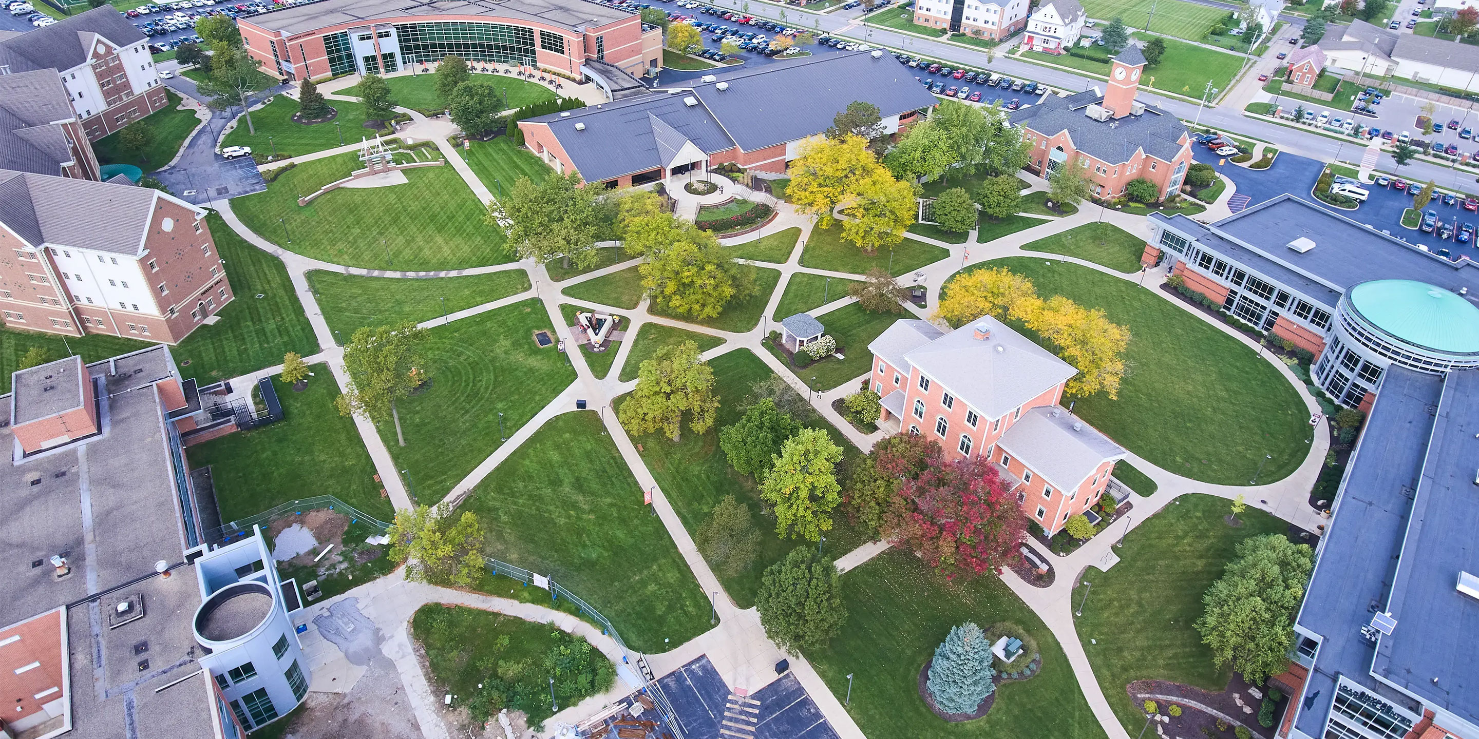 Green lawns, winding paths, academic buildings under clear sky.