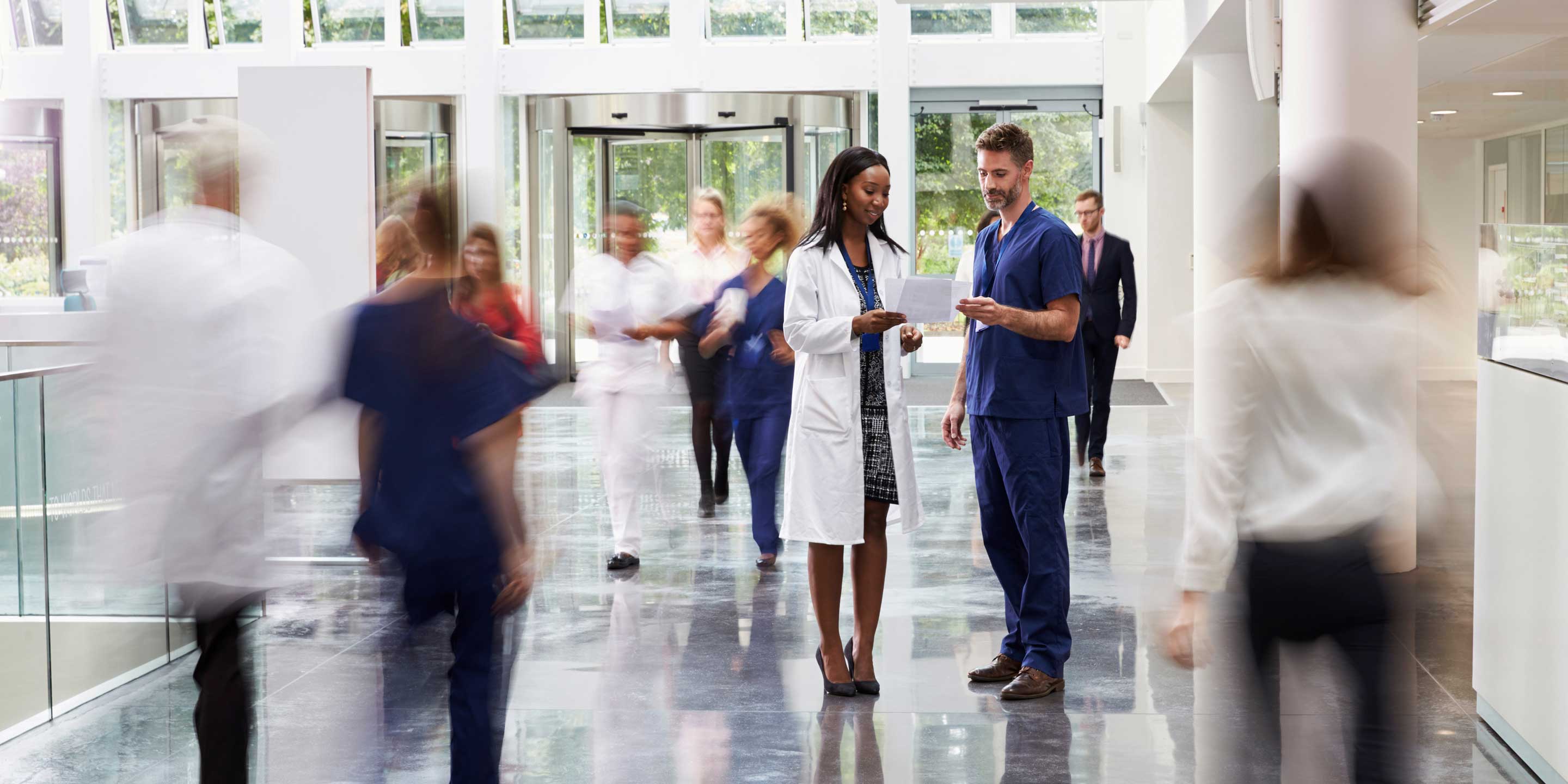 Staff In Busy Lobby Area Of Modern Hospital
