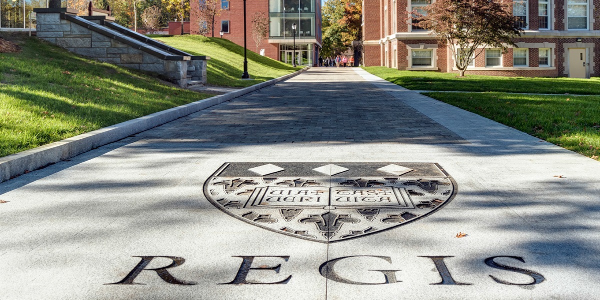 Regis College logo displayed on the ground at the entrance of the campus