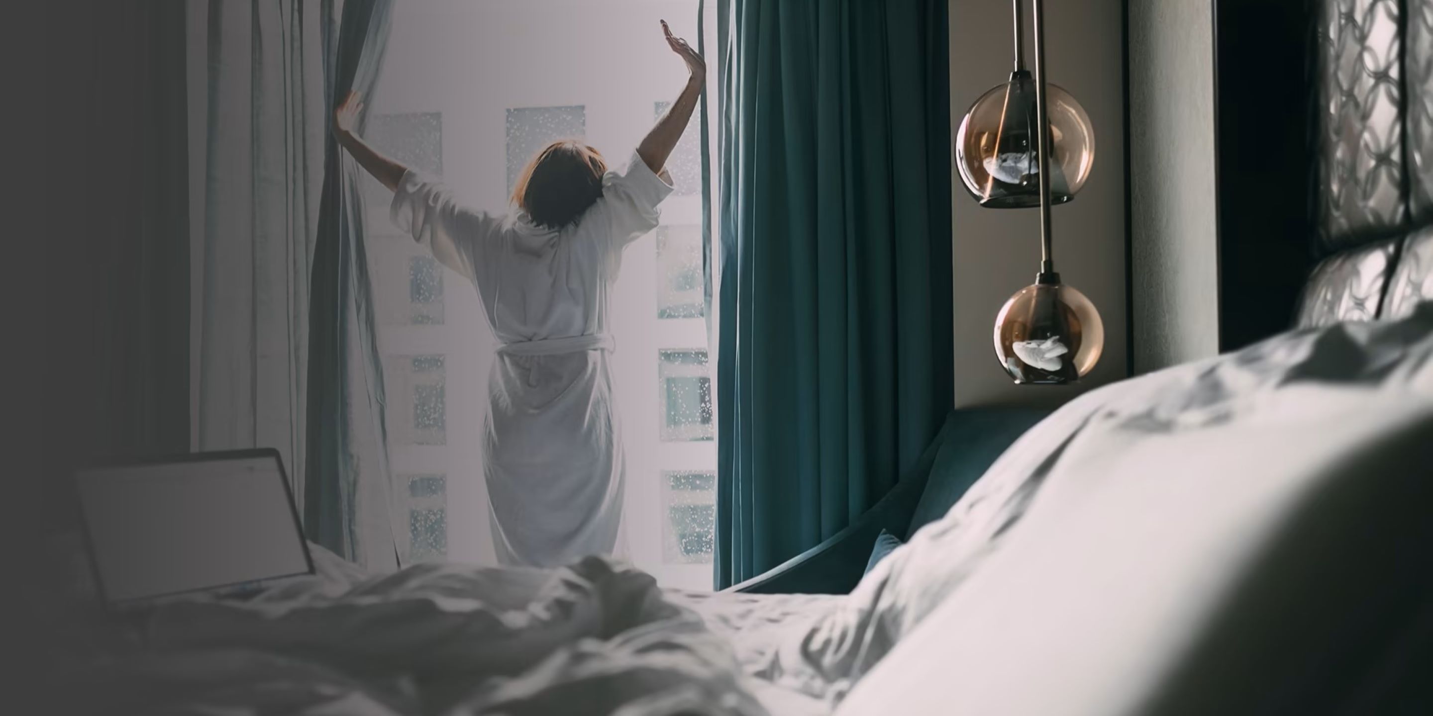 Experience the calm of a new day with this serene hotel room scene. Featuring soft natural light, modern pendant lighting, and cozy white linens, this image captures the essence of comfort and relaxation in hospitality design.