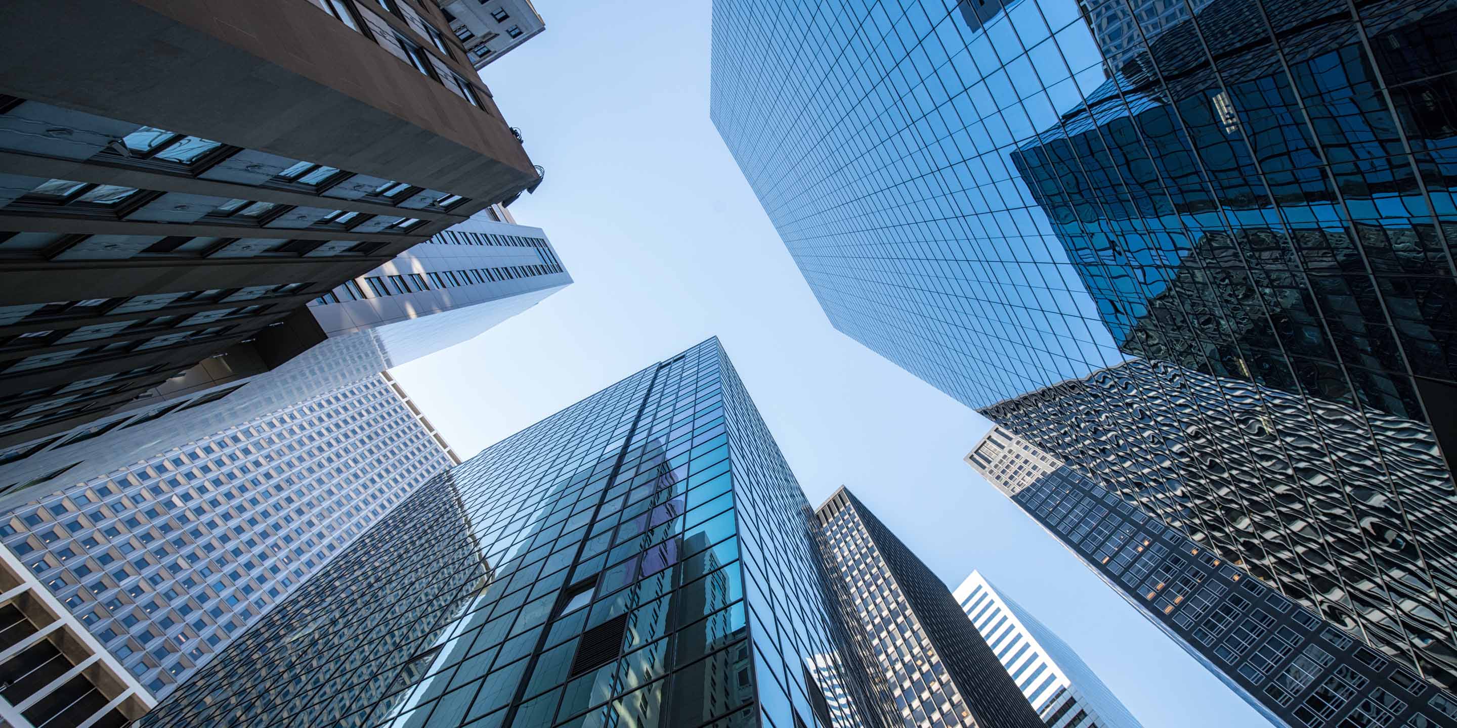 Reflective glass buildings rise high into the blue sky.