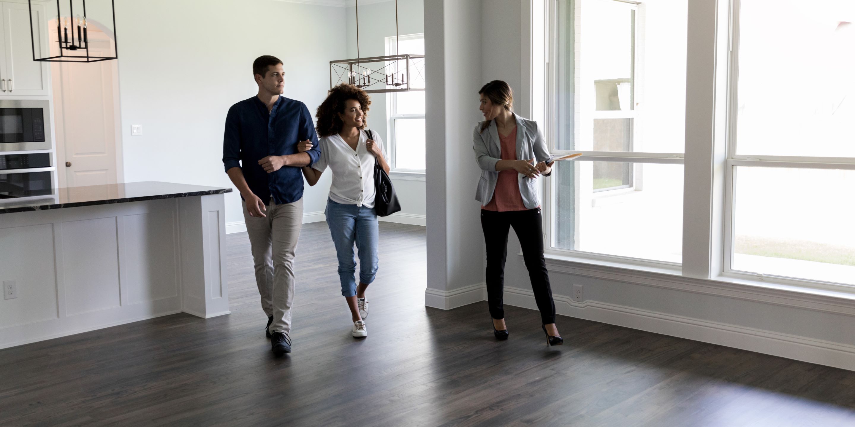 Female real estate presenting an empty house to a couple