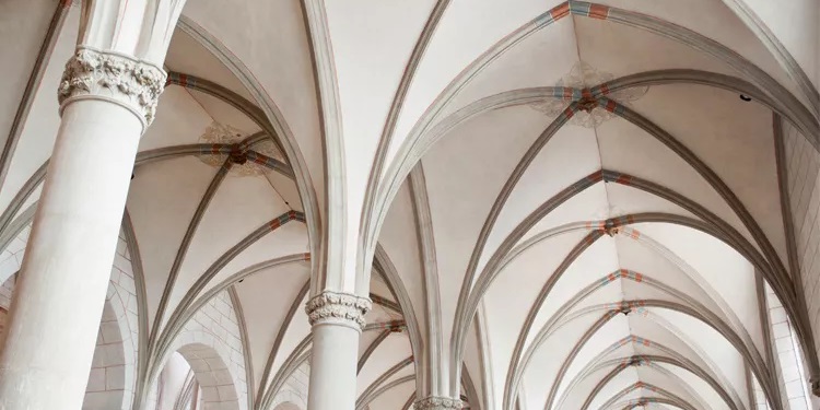 Explore the breathtaking architecture of a Gothic cathedral interior featuring intricate ribbed vaults, elegant columns, and detailed stone carvings. This image captures the grandeur and beauty of historical church design.