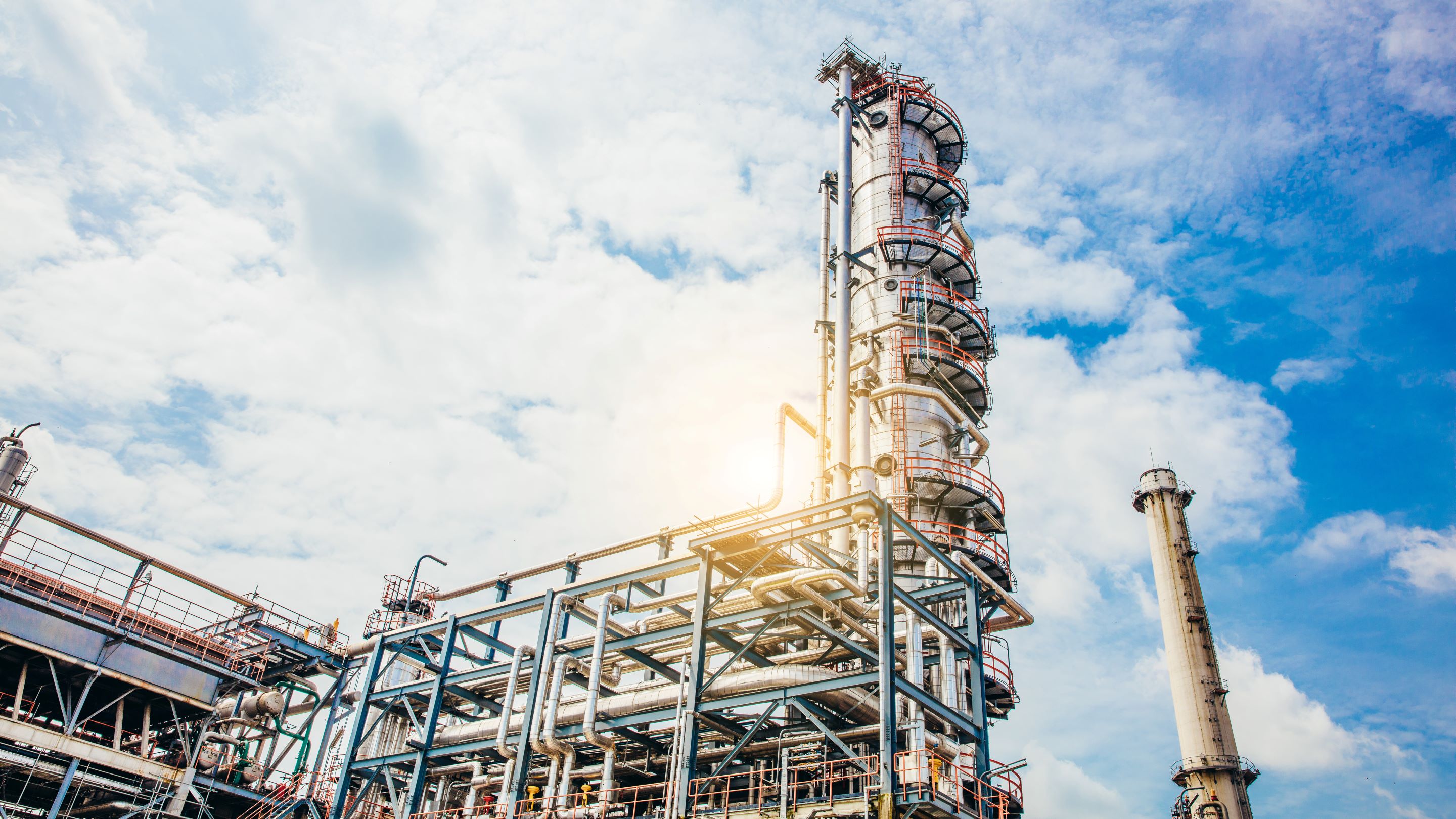 A chemical processing plant rises against a clear sky, showcasing industrial architecture and engineering