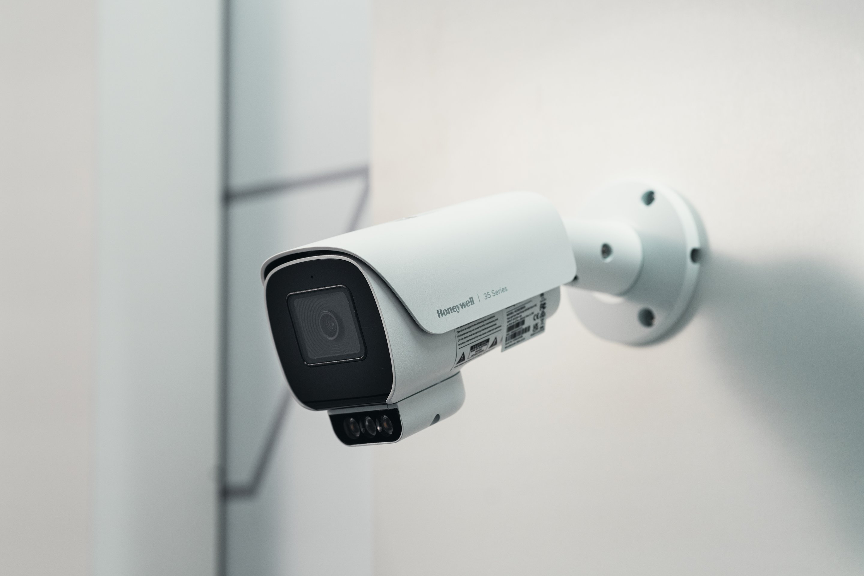 A professional-grade Honeywell 35 Series bullet surveillance camera mounted on a clean white wall for industrial monitoring.