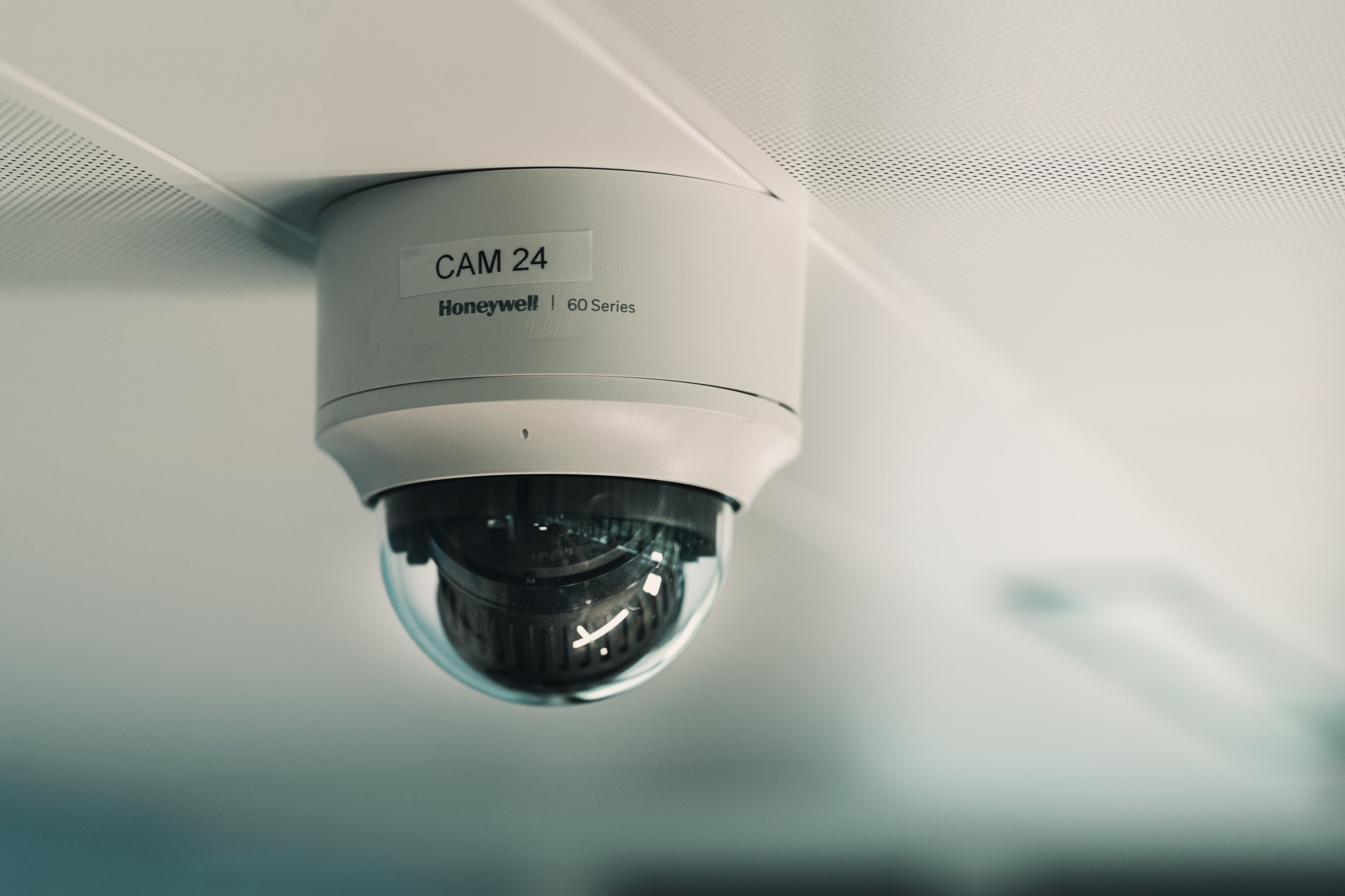 A low-angle close-up of a Honeywell 60 Series dome security camera mounted on a textured white ceiling.