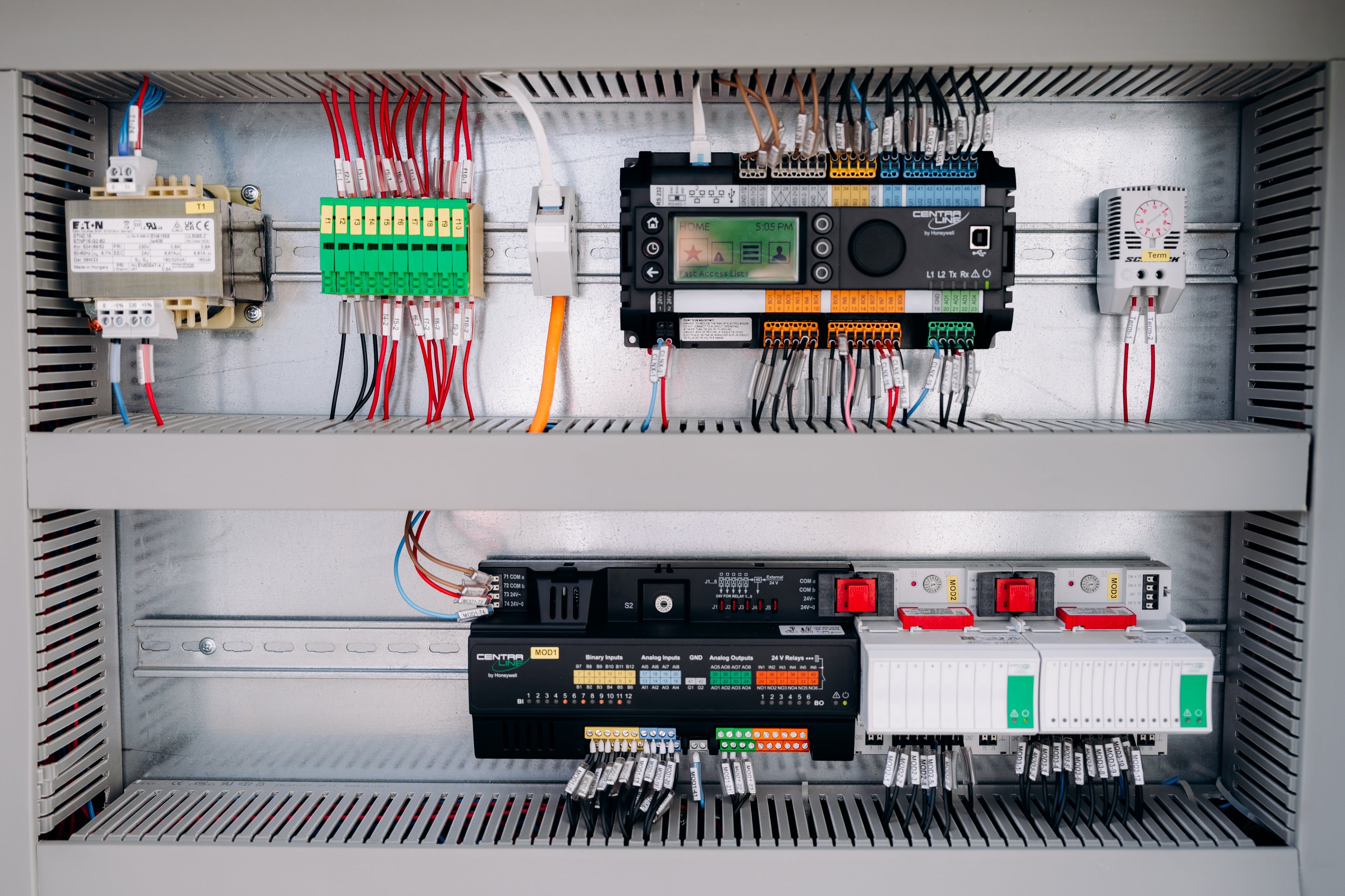 A detailed view of organized industrial electrical components and wiring inside a mounted control cabinet.