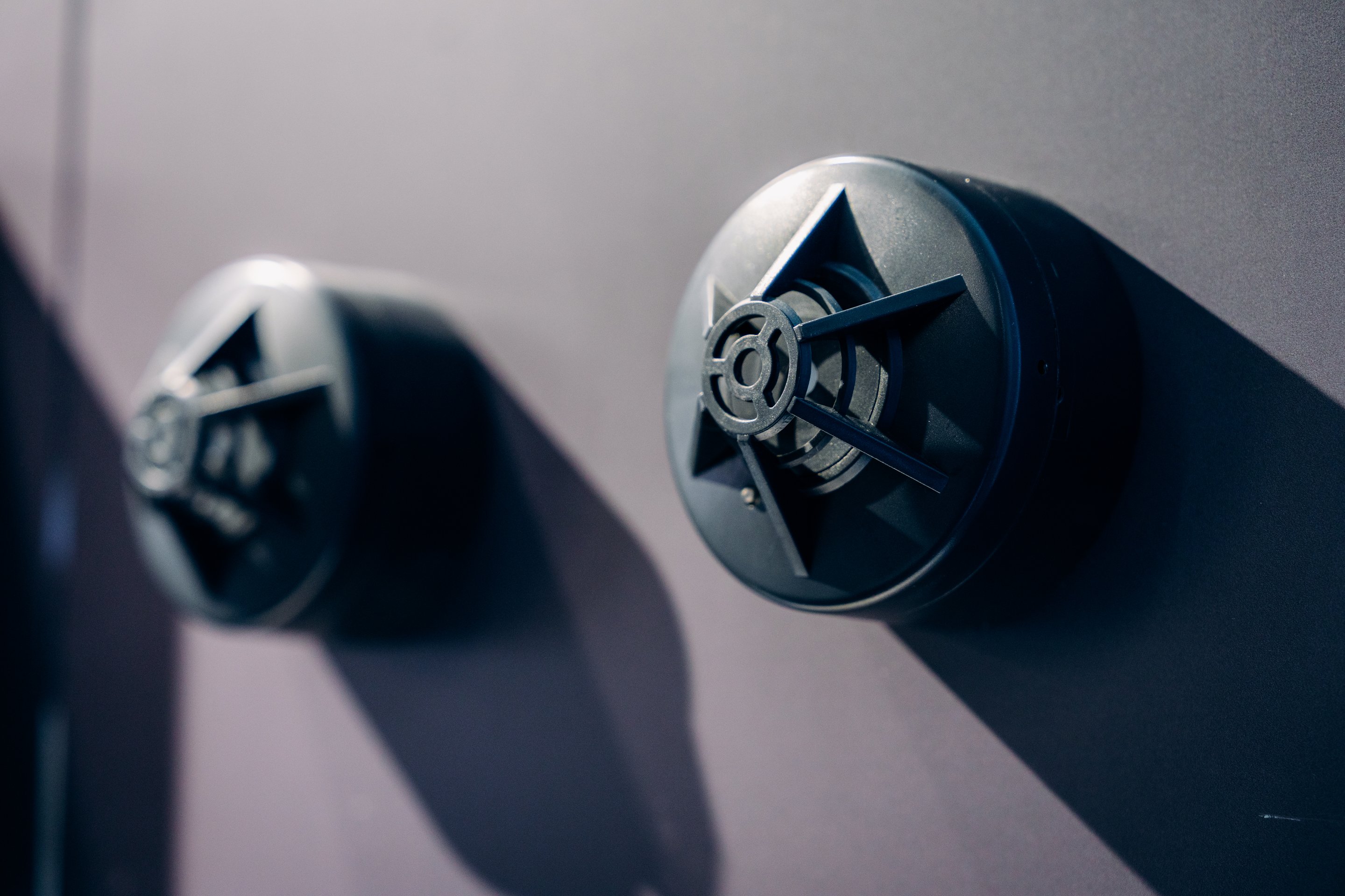 Close-up view of circular industrial sensors mounted on a smooth grey surface, emphasizing geometric design and dramatic lighting shadows.