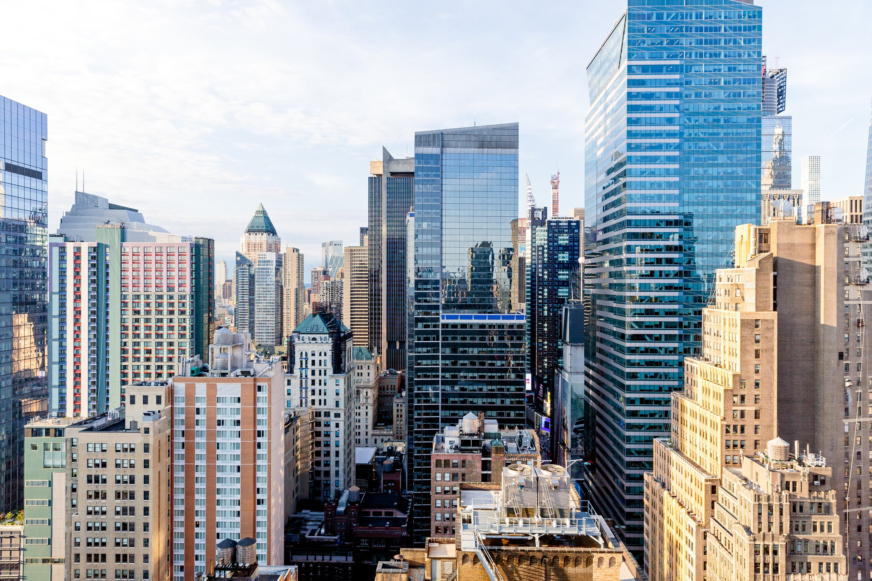 An elevated wide-angle view of the diverse architectural landscape of Midtown Manhattan captured in the soft morning light.