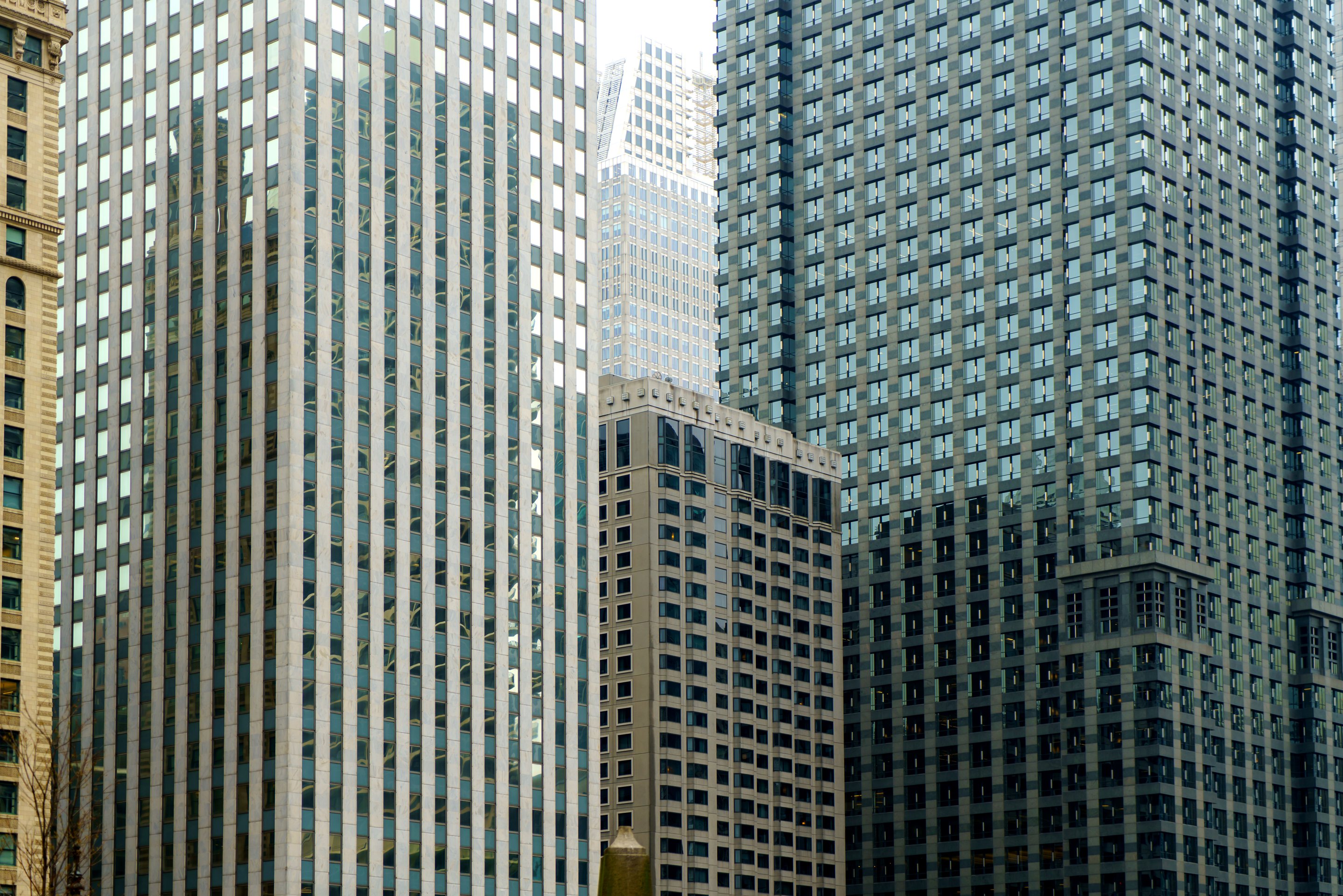 Abstract low-angle perspective captures the geometric patterns and contrasting glass facades of modern high-rise office buildings in a dense city center.