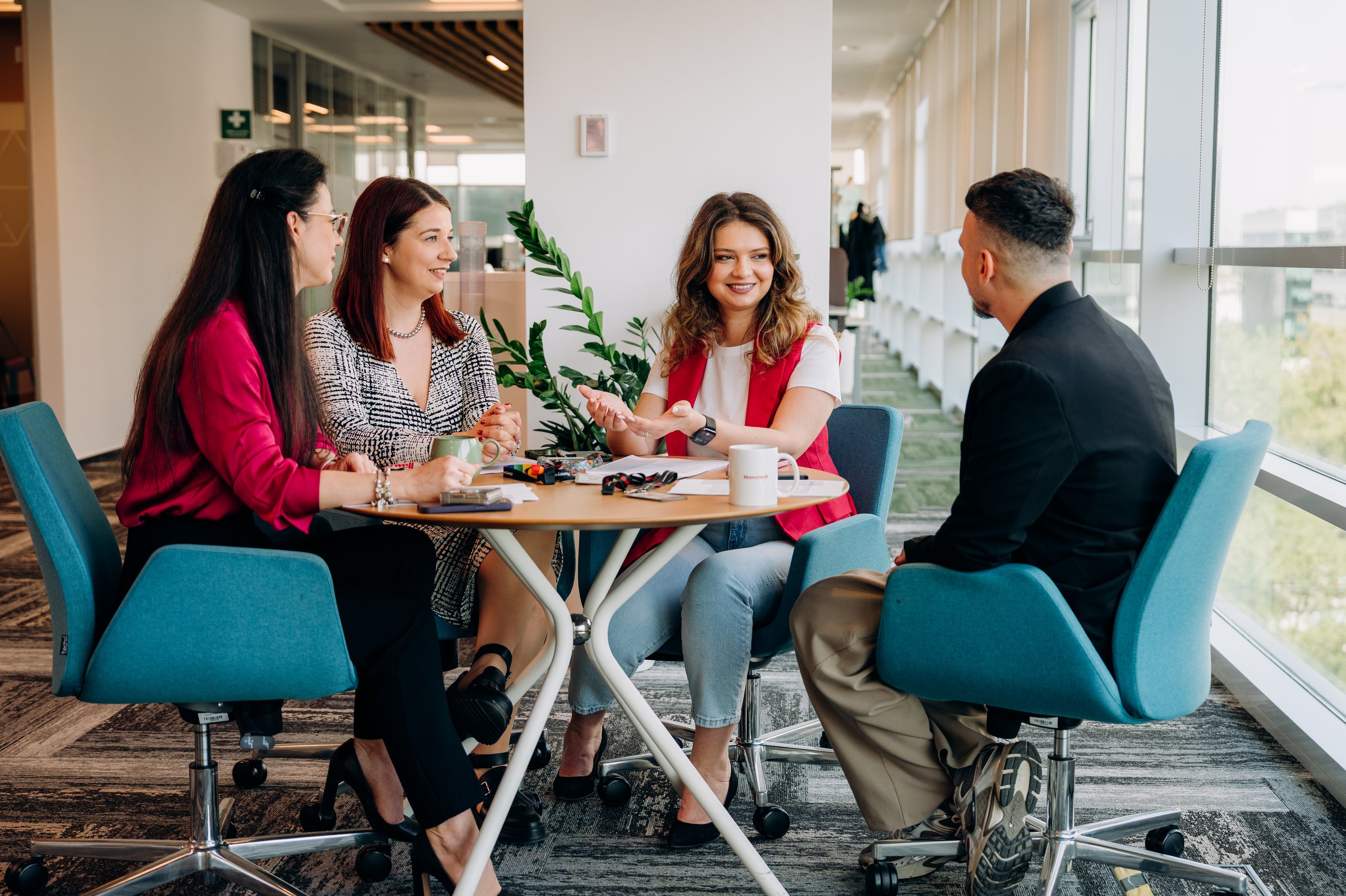 A diverse group of four professionals collaborates during a productive strategy session in a modern, sunlit office environment.