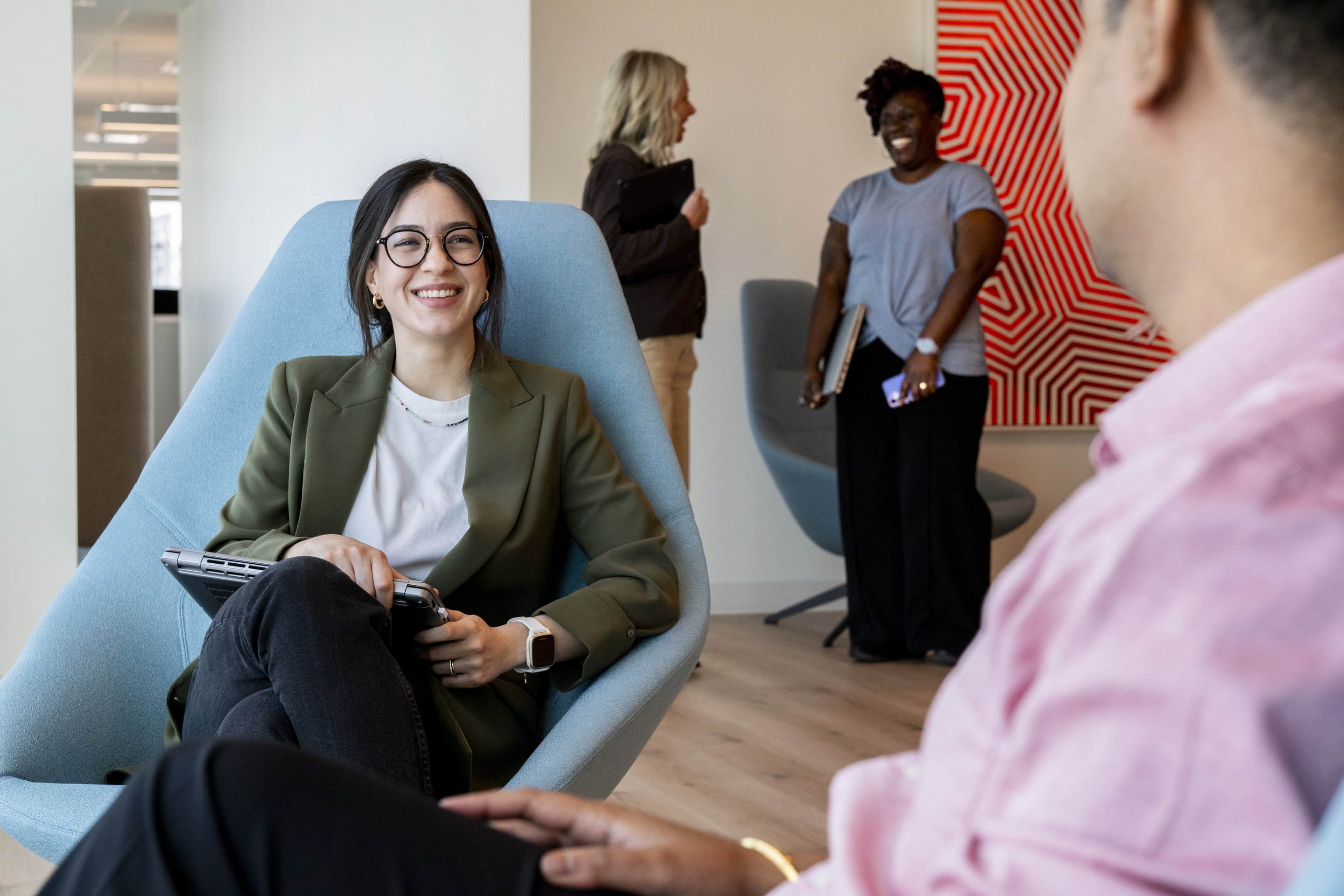 Diverse business team members engaging in a collaborative discussion within a modern office lounge setting.