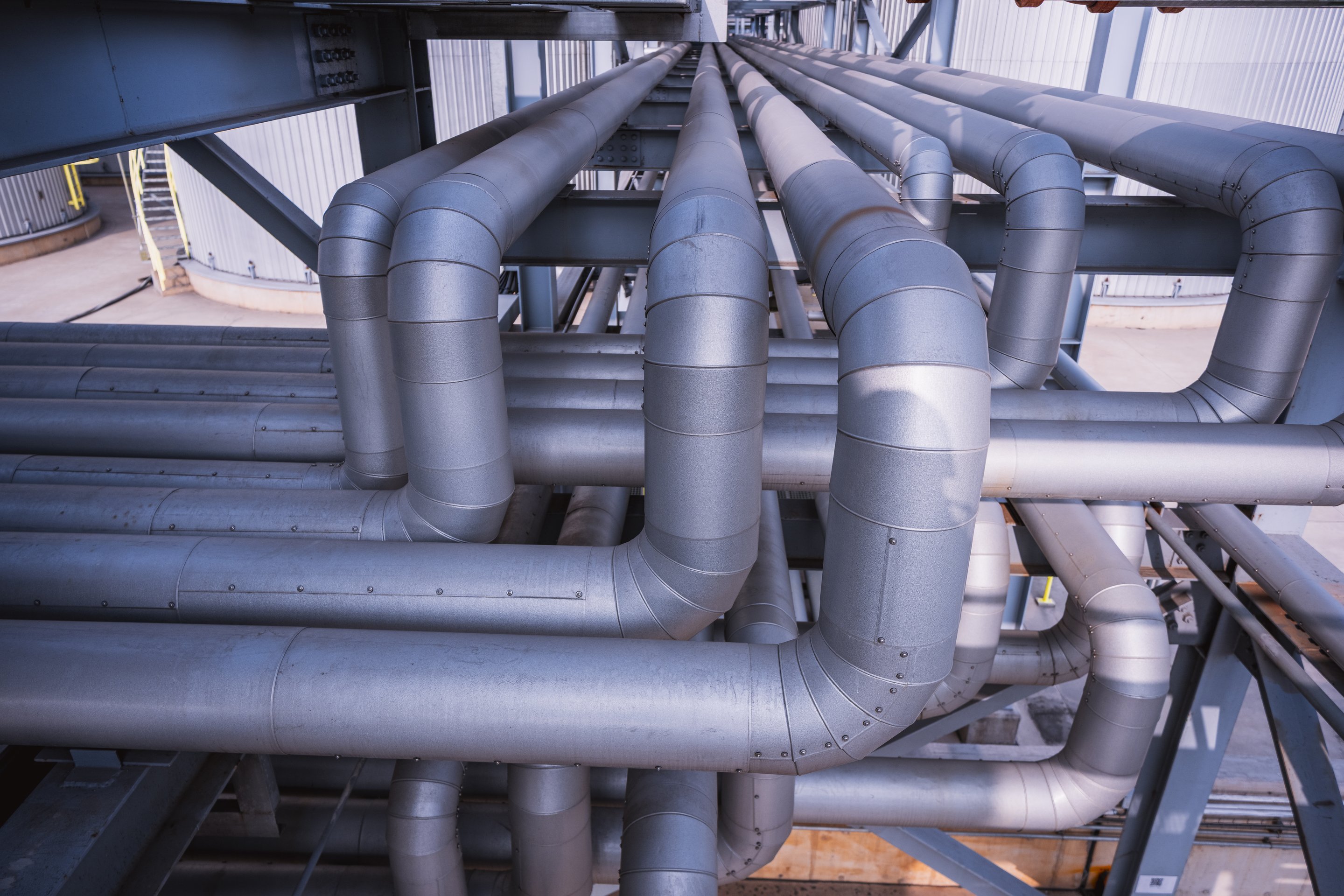A complex network of insulated metal pipes and support structures at an industrial processing facility.