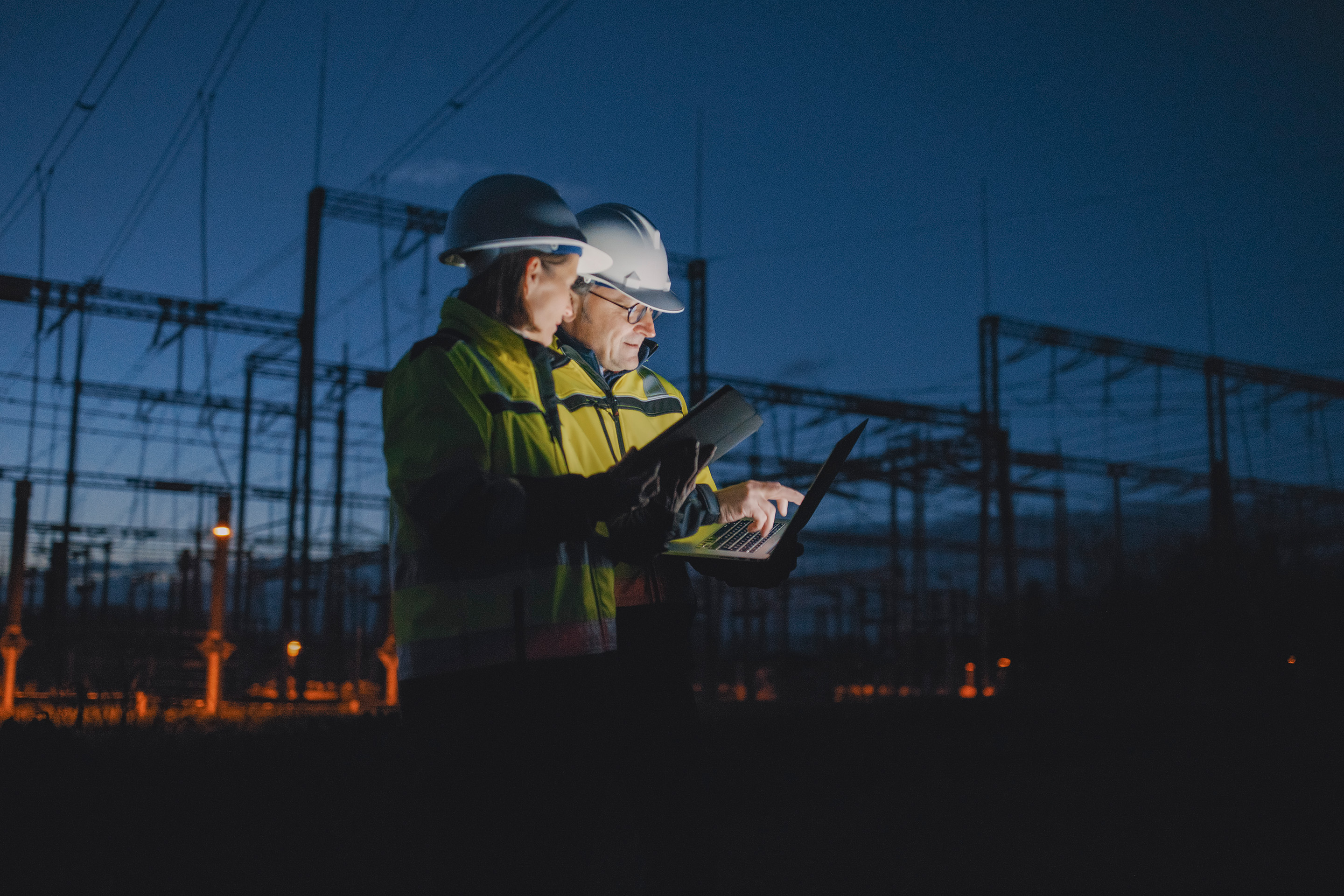 Technician analysing equipment using a tablet in an industrial plant, highlighting predictive maintenance, digital services, and operational efficiency in manufacturing.