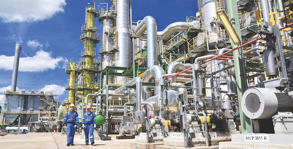 chemical industry plant - workers in work clothes in a refinery with pipes and machinery