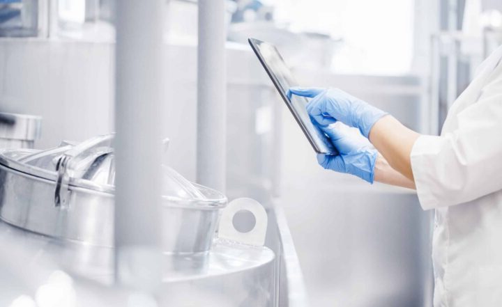 Operator uses tablet computer to check quality and temperature of yeast fermentation in tanker hops and malt, beer production.