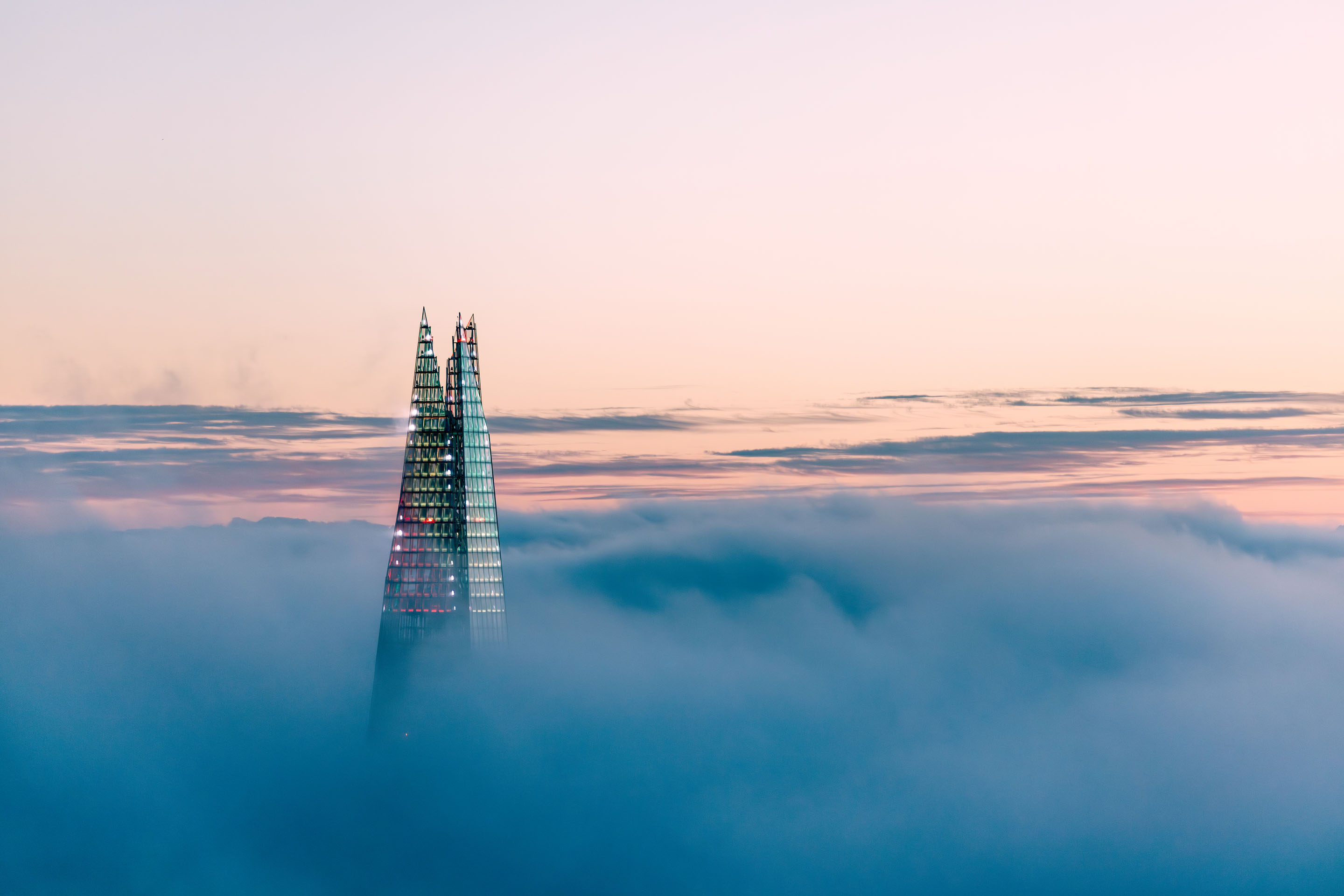 hon-glass-skyscraper-spire-above-clouds-sunset-cityscape-2183875160.jpg
