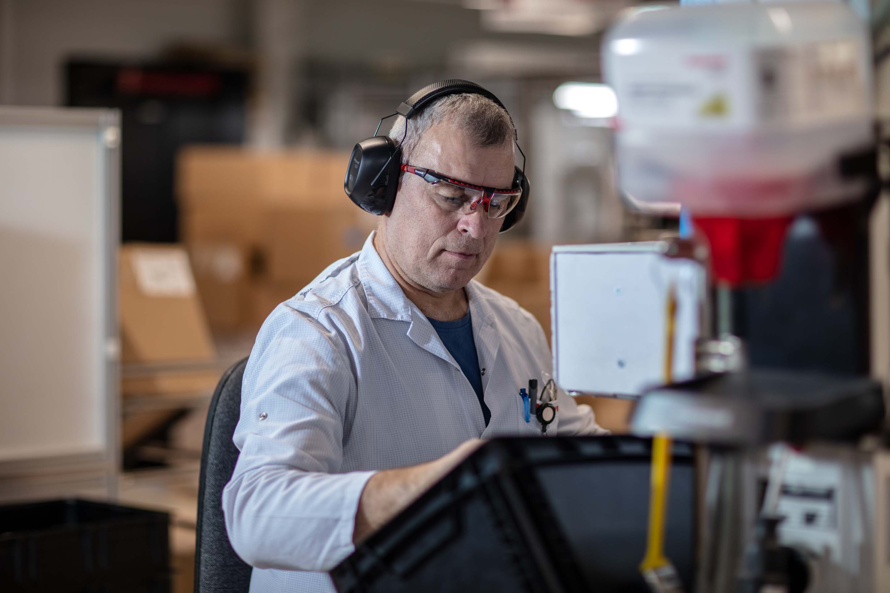 Technician Monitoring Machinery with Protective Gear in Factory Environment