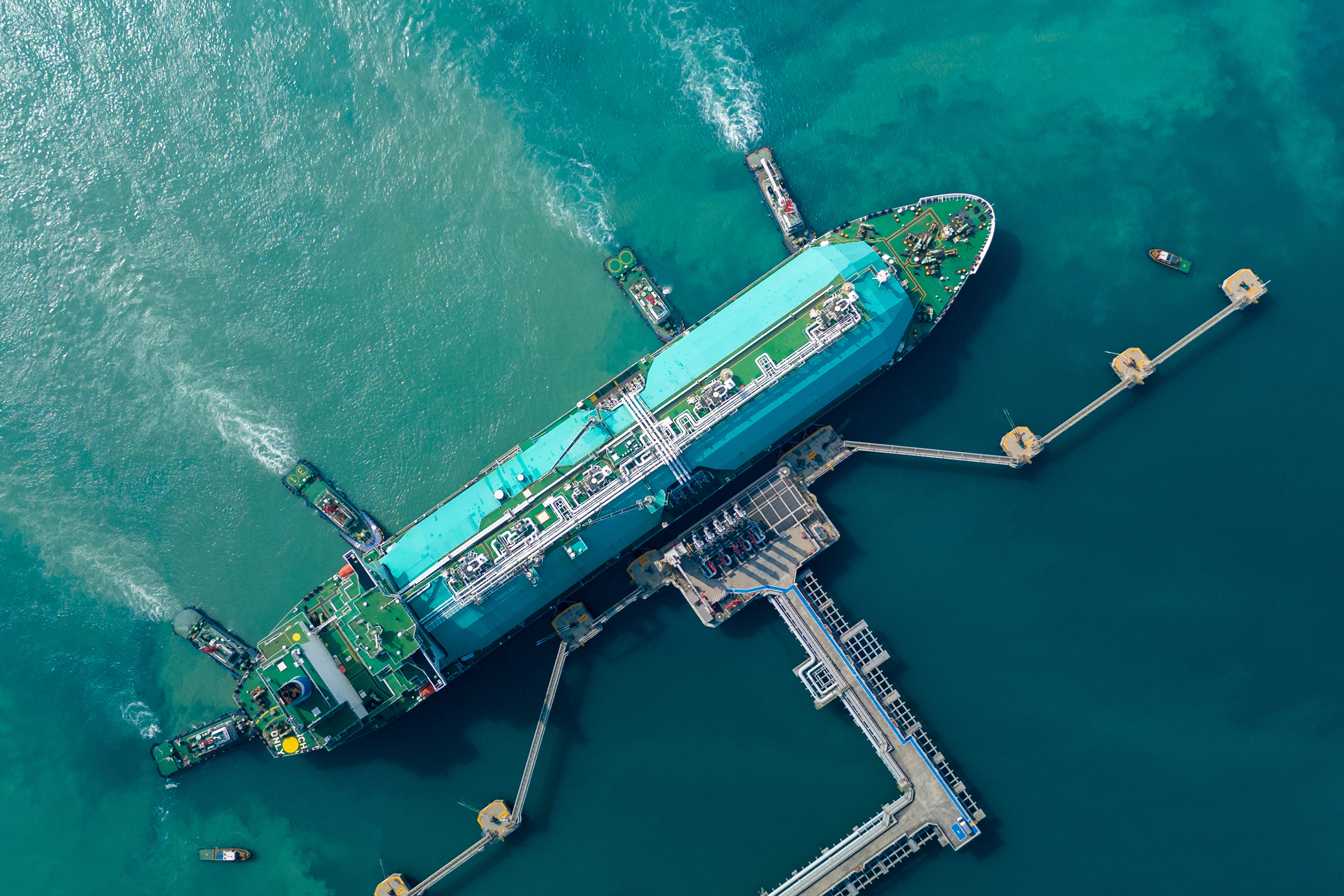 Aerial view of an LNG carrier docked at a marine terminal, showcasing liquefied natural gas logistics, maritime operations, and energy supply chain infrastructure.
