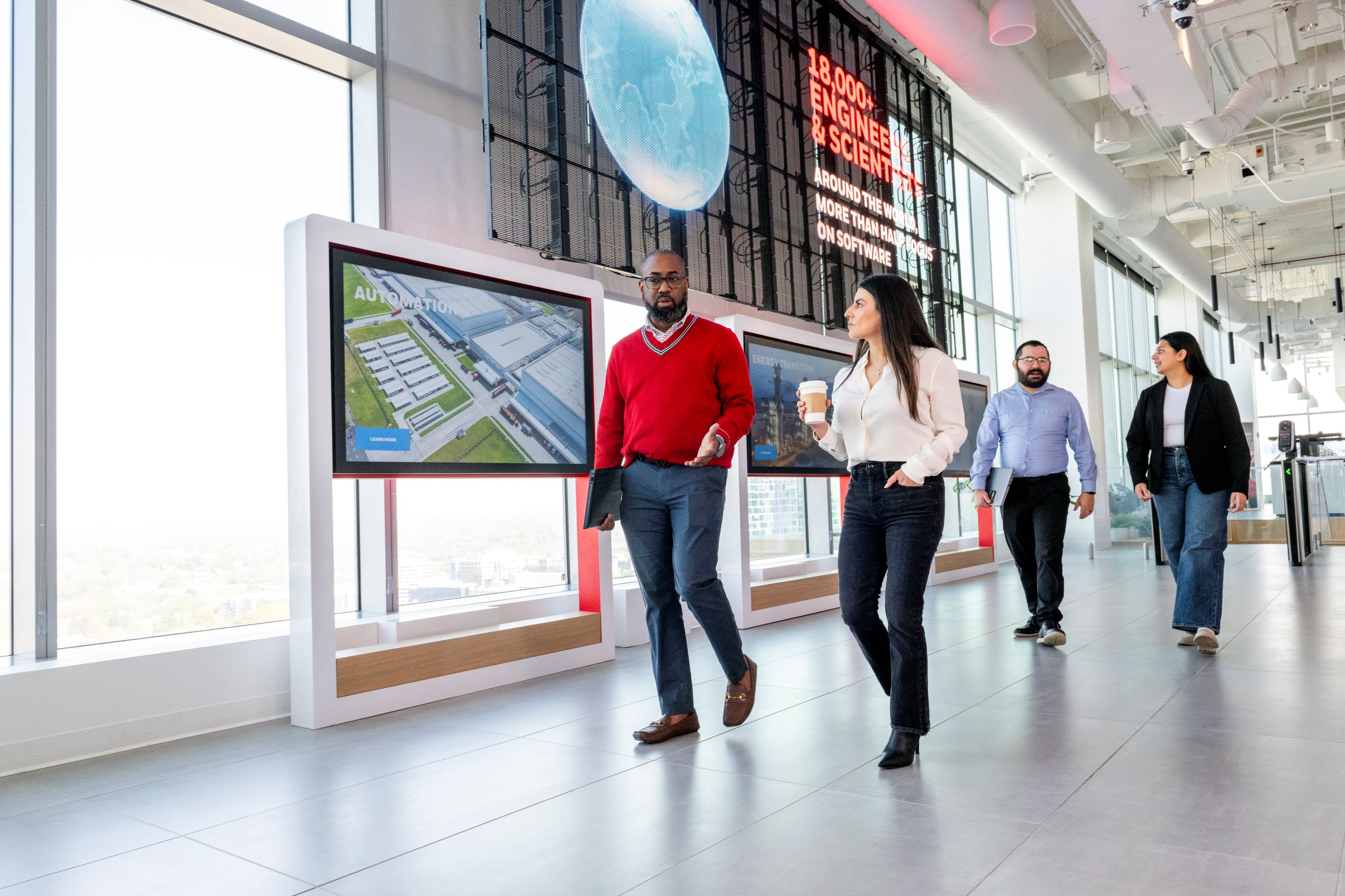 A business meeting at Honeywell with a speaker presenting to a group of professionals, showcasing teamwork and innovation in a modern office space.