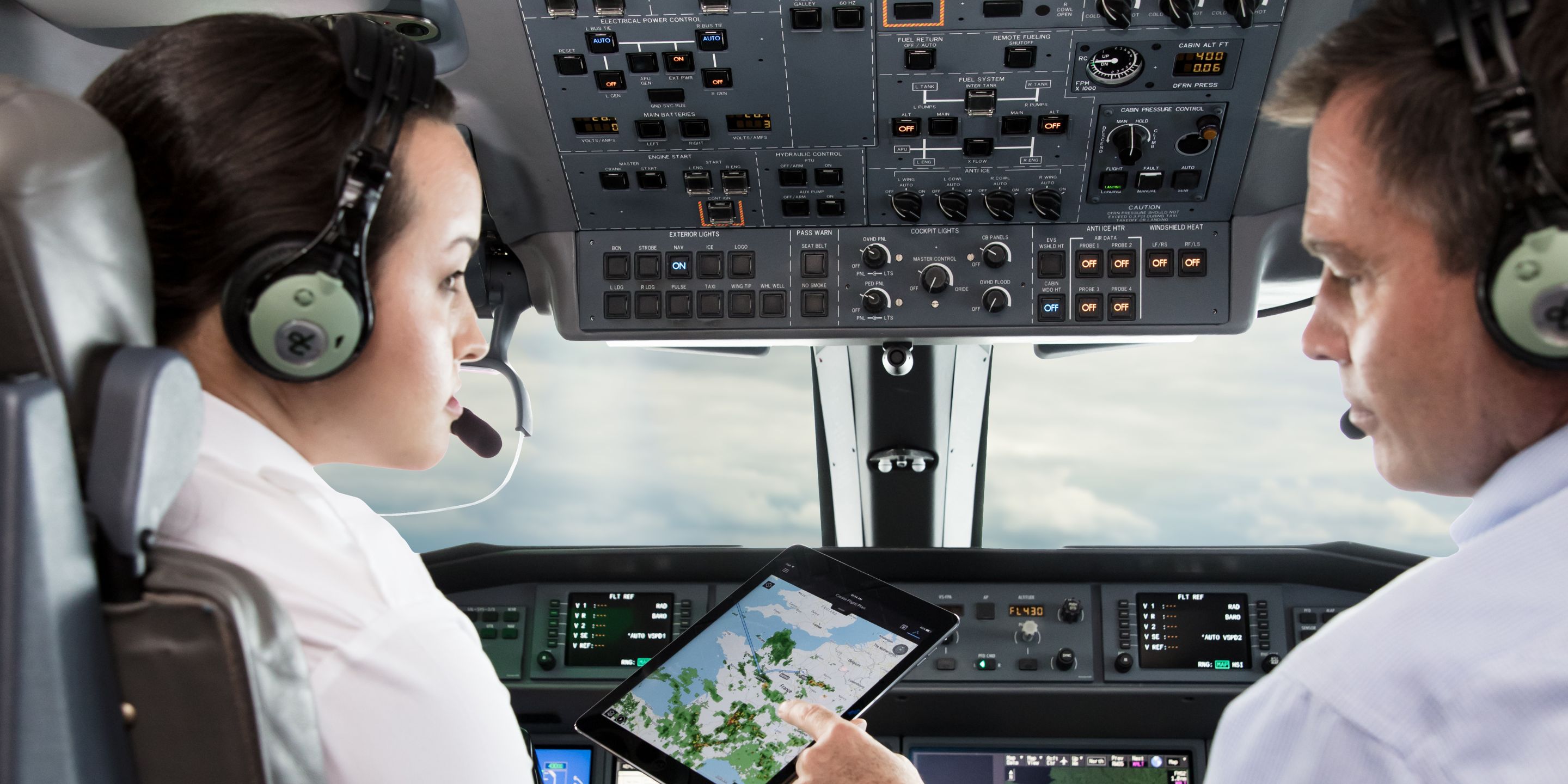Two pilots analyze a weather screen in the airplane cockpit