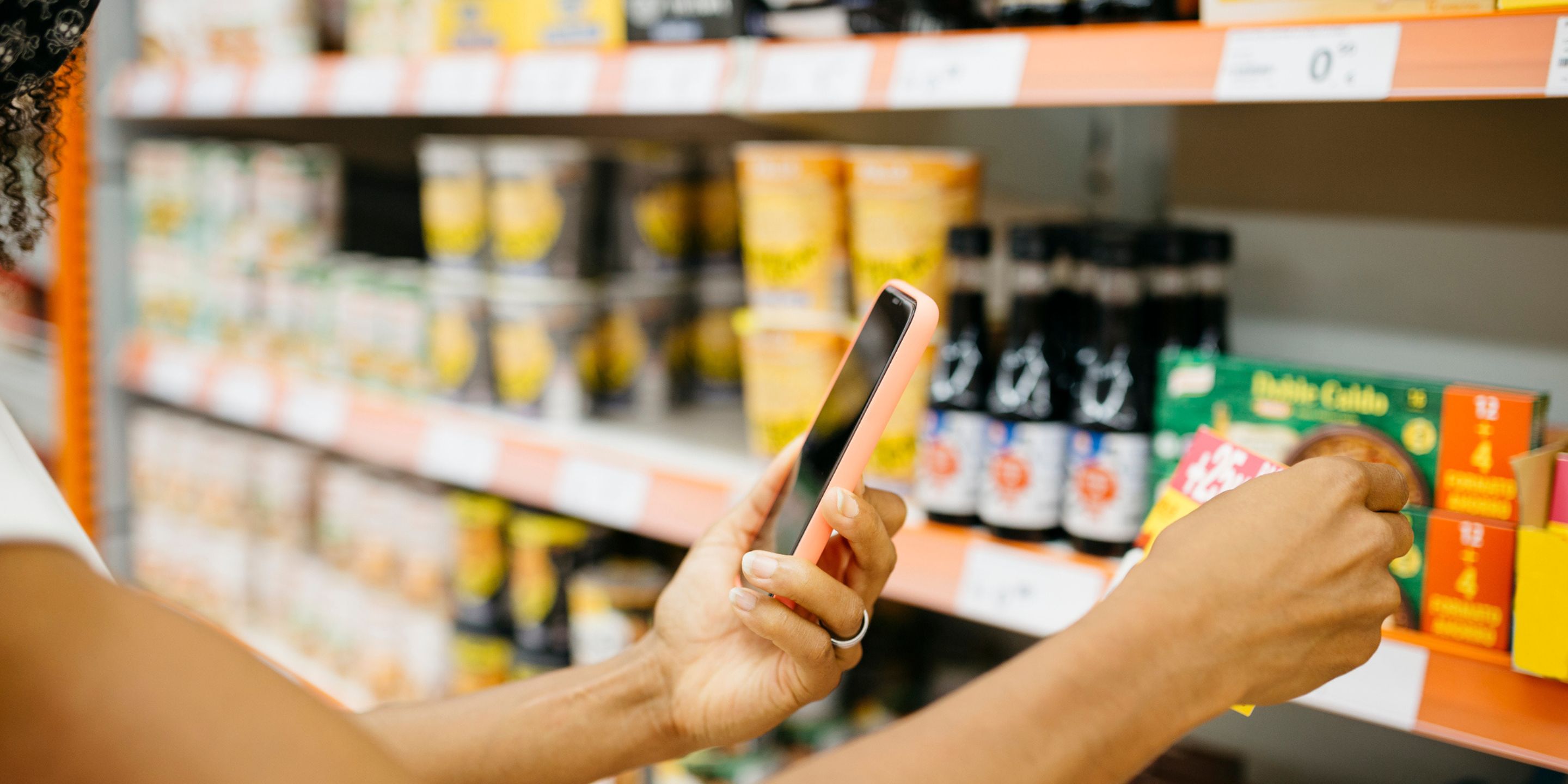 A shopper uses their phone to scan or take a photo of a product on the shelf.