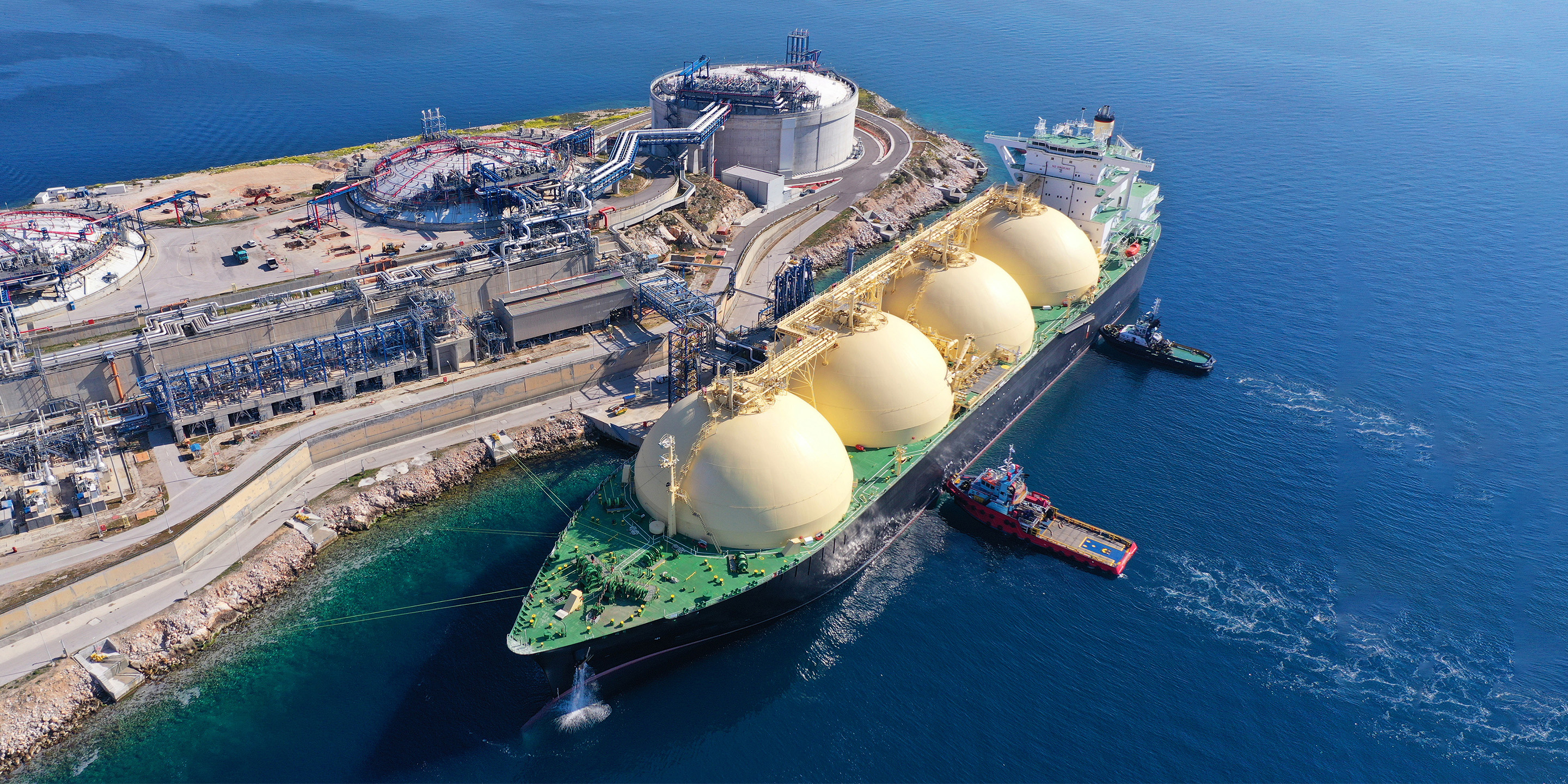Liquified Natural Gas tanker anchored in small gas terminal island with tanks