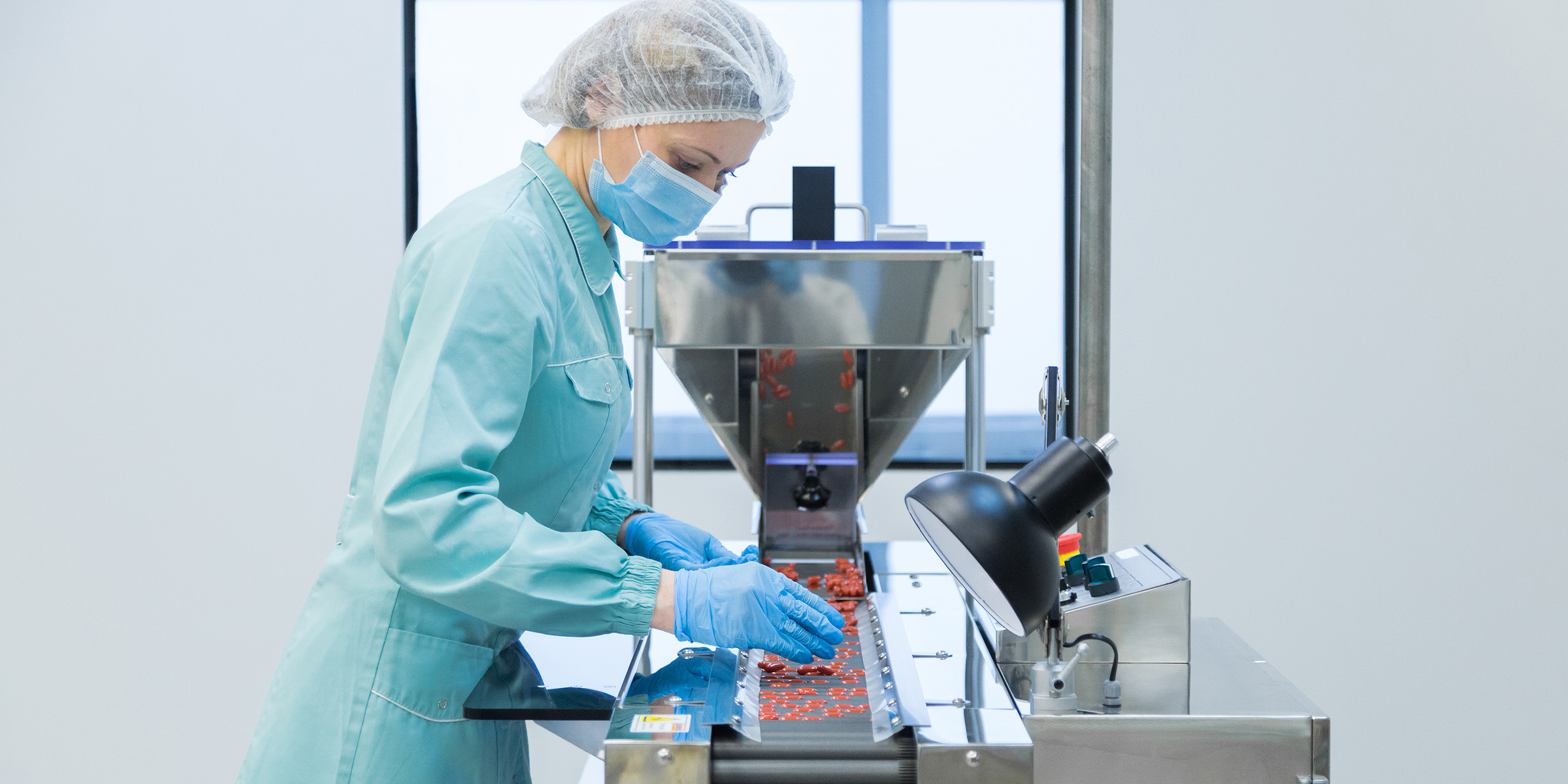 A technician in protective clothing manages equipment in a life science lab, focusing on precise handling of materials in a sterile environment.