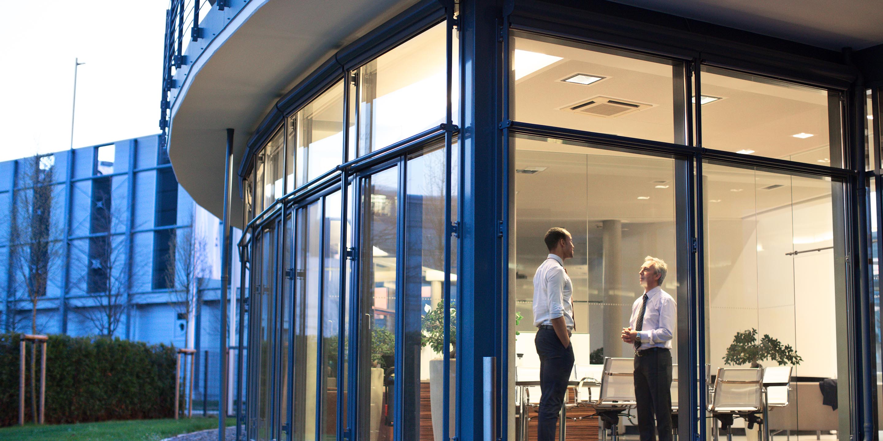 Two businessmen standing in modern office discussing work