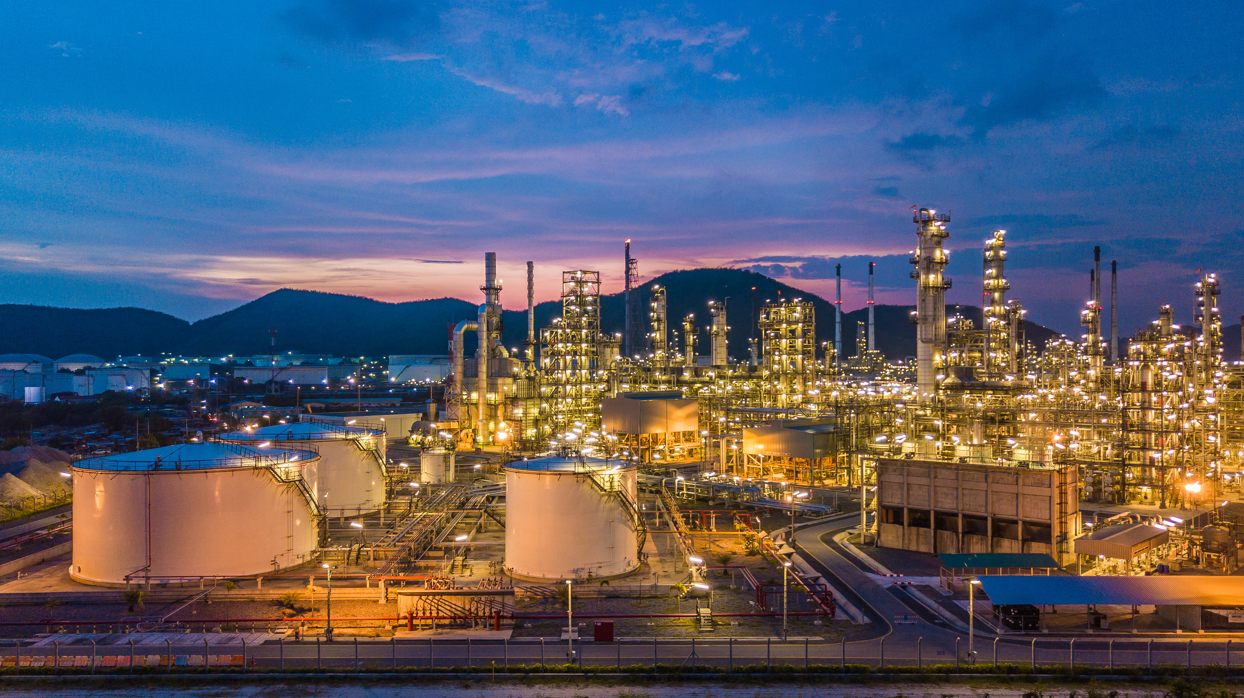 Aerial top view oil and gas chemical tank with oil refinery plant background at twilight.